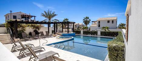 Alberca al aire libre, sombrillas en la alberca y camastros