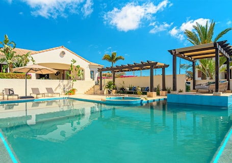 Una piscina al aire libre, sombrillas, sillones reclinables de piscina