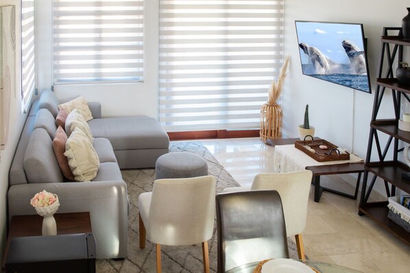 Un salon moderne avec un canapé gris, une table basse et un téléviseur diffusant une scène de la nature.