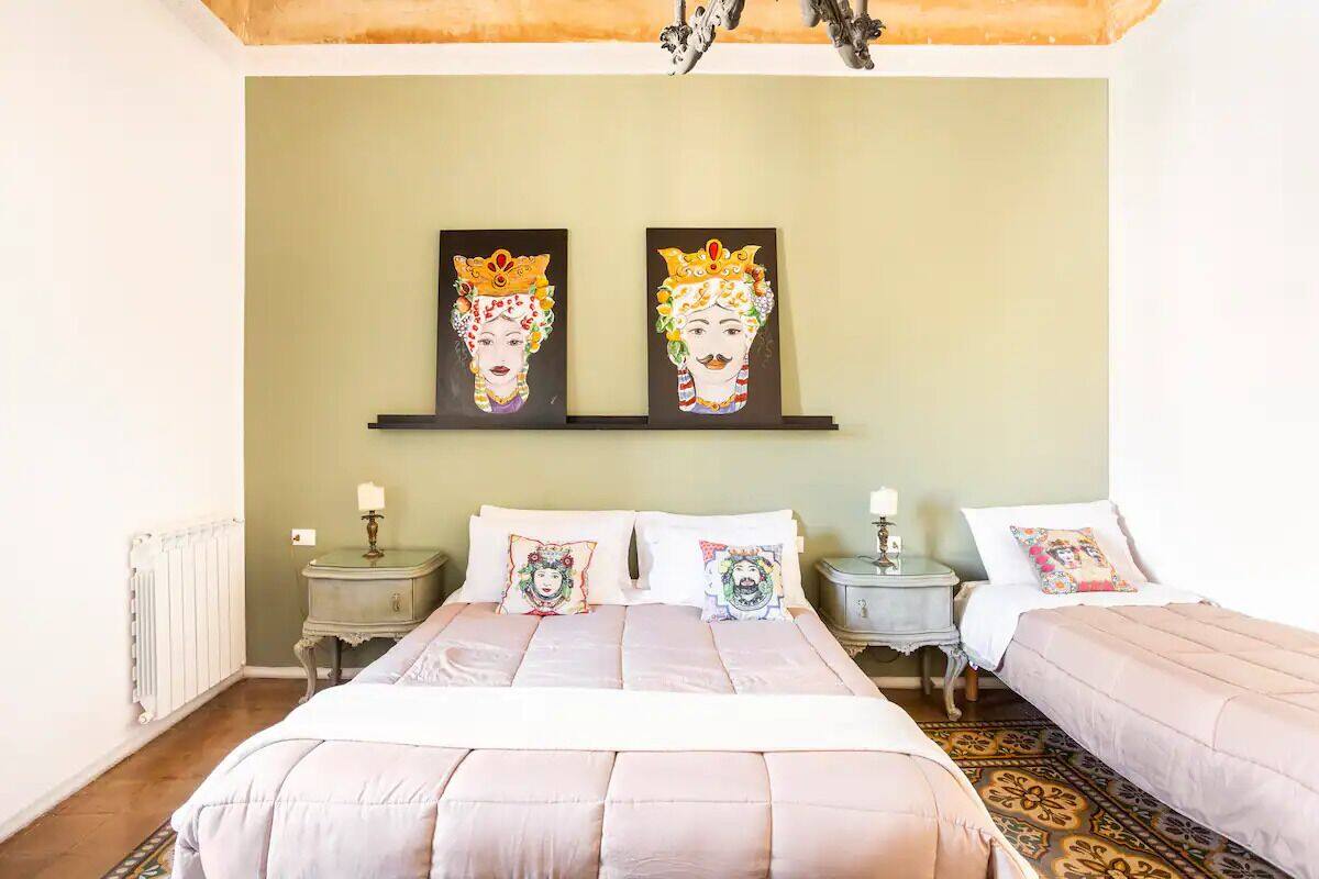 A bedroom with two beds, a radiator, and artwork on the wall.