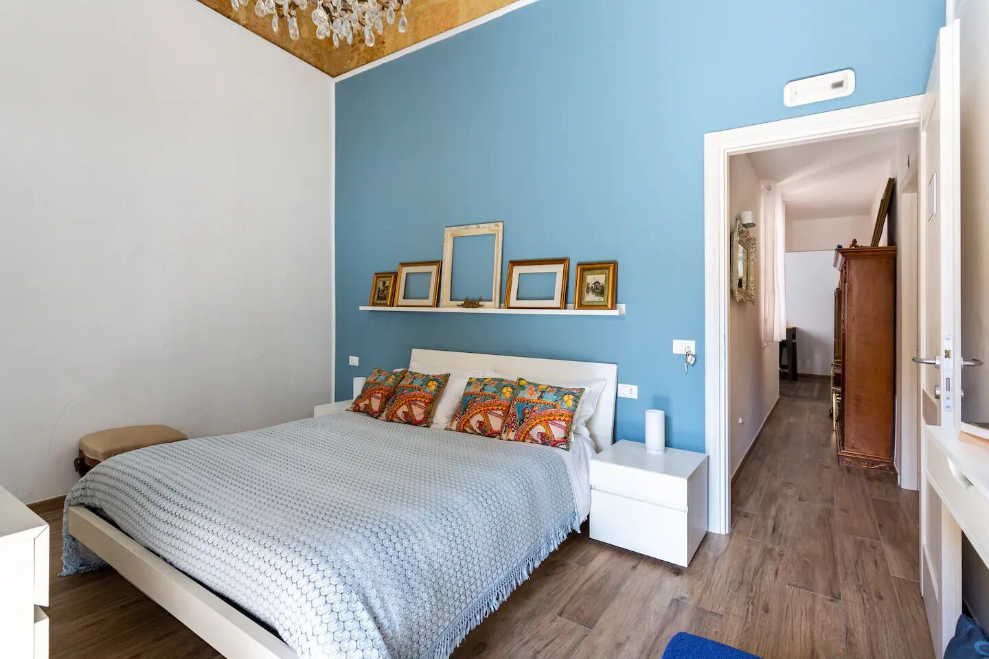 A bedroom with a bed, bedside tables, a nightstand, and a wooden wardrobe.
