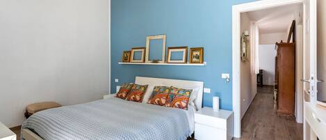 A bedroom with a bed, bedside tables, a nightstand, and a wooden wardrobe.