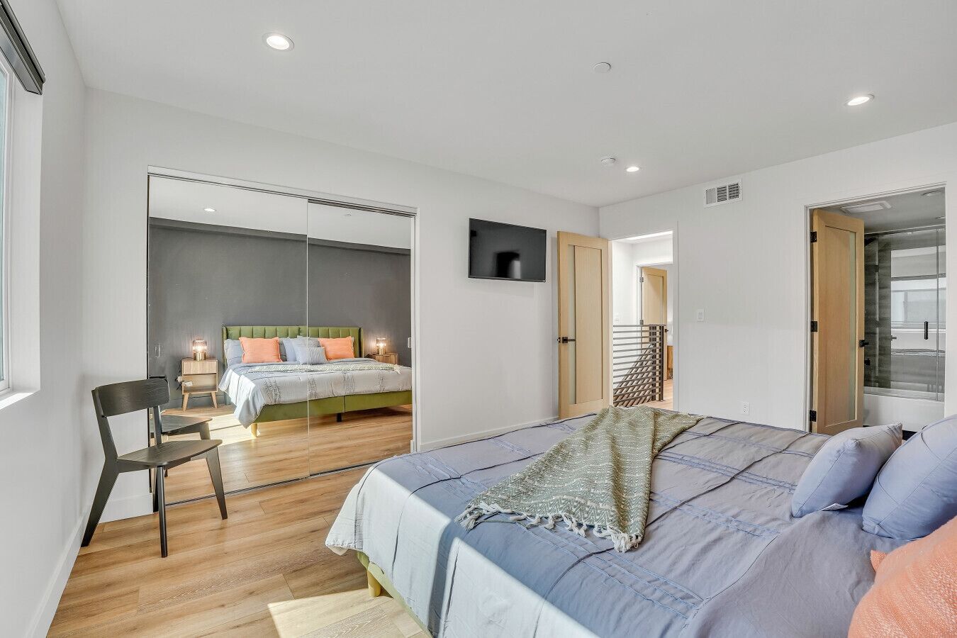 Een moderne slaapkamer met een groot bed, een stoel, een bureau en een televisie.