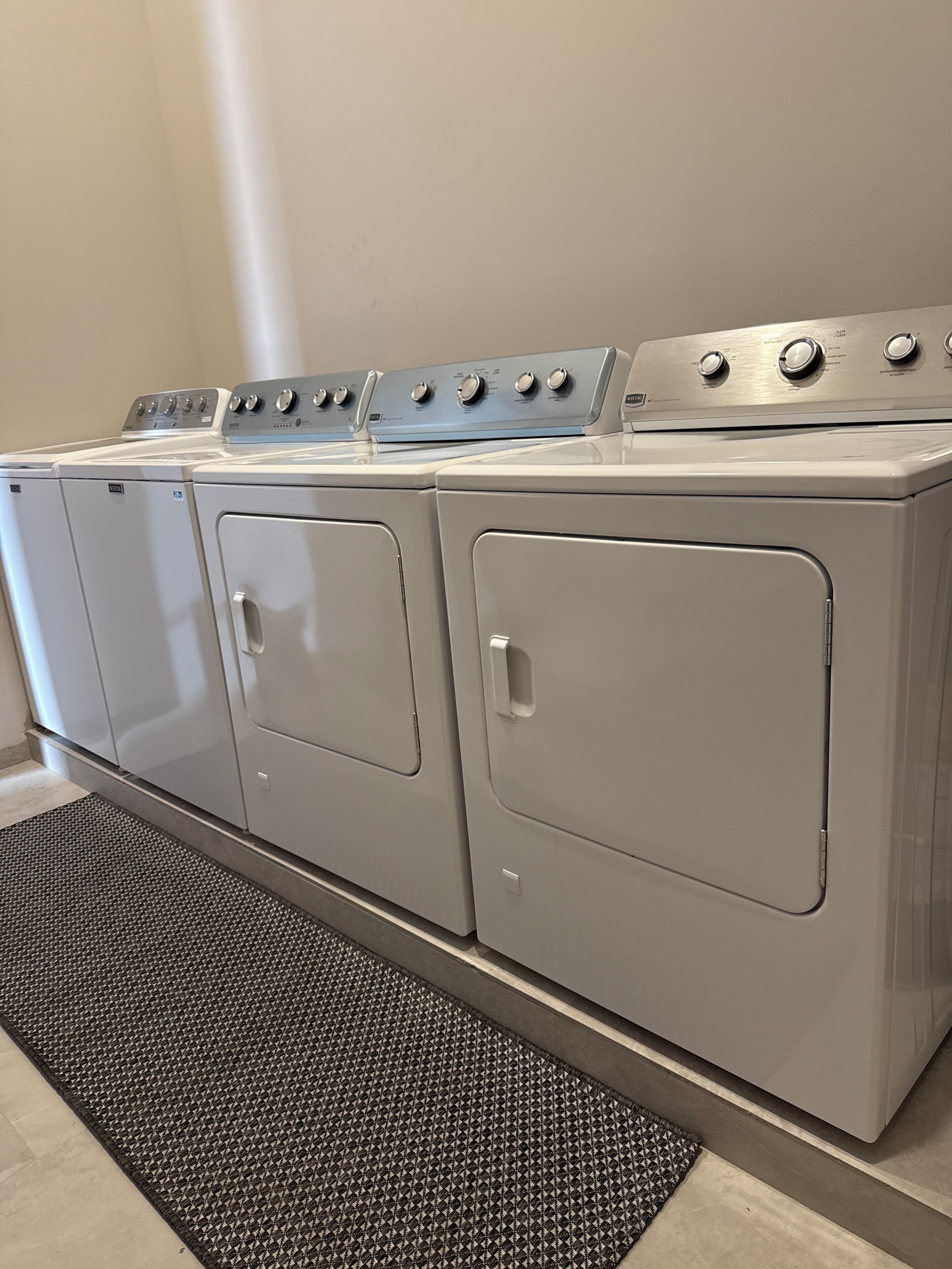 A row of front-loading washers and dryers in a laundry room.