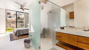A modern bathroom with a glass shower enclosure, a wooden vanity, and a large mirror.