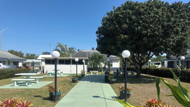 A pathway leading to a building with outdoor seating and potted plants. - Tropical Palm Motel (North Fort Myers)