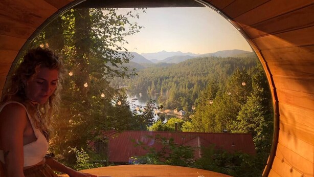 A circular wooden structure with a view of a forest and mountains.