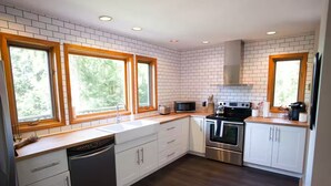 A modern kitchen with white cabinets, a stainless steel oven, a microwave, and a dishwasher.