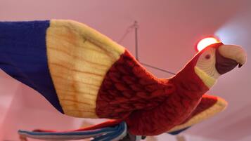 Un jouet en peluche représentant un perroquet, aux couleurs rouge, jaune et bleu.