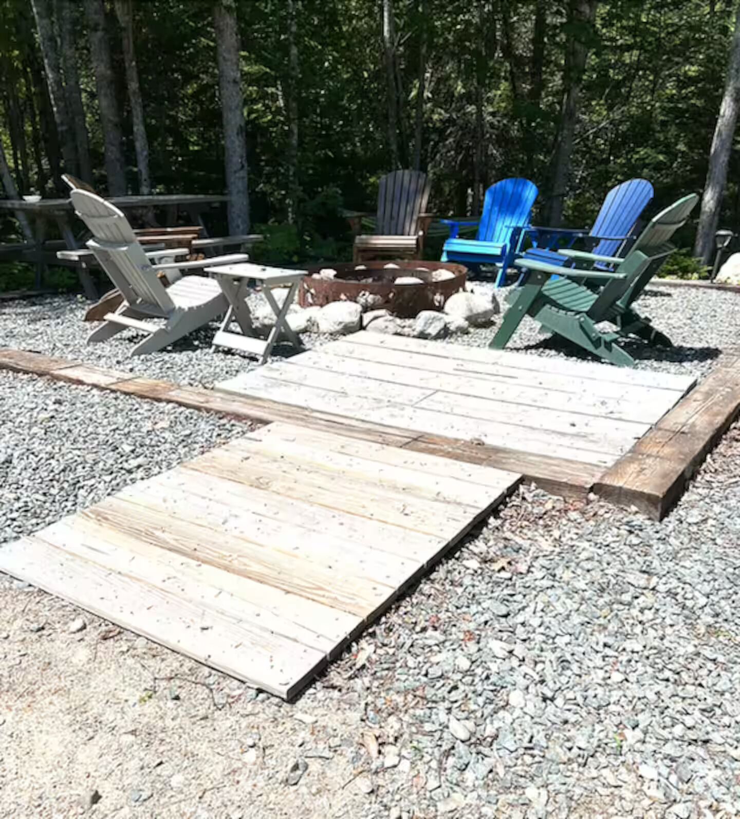 A wooden deck with Adirondack chairs and a fire pit area.