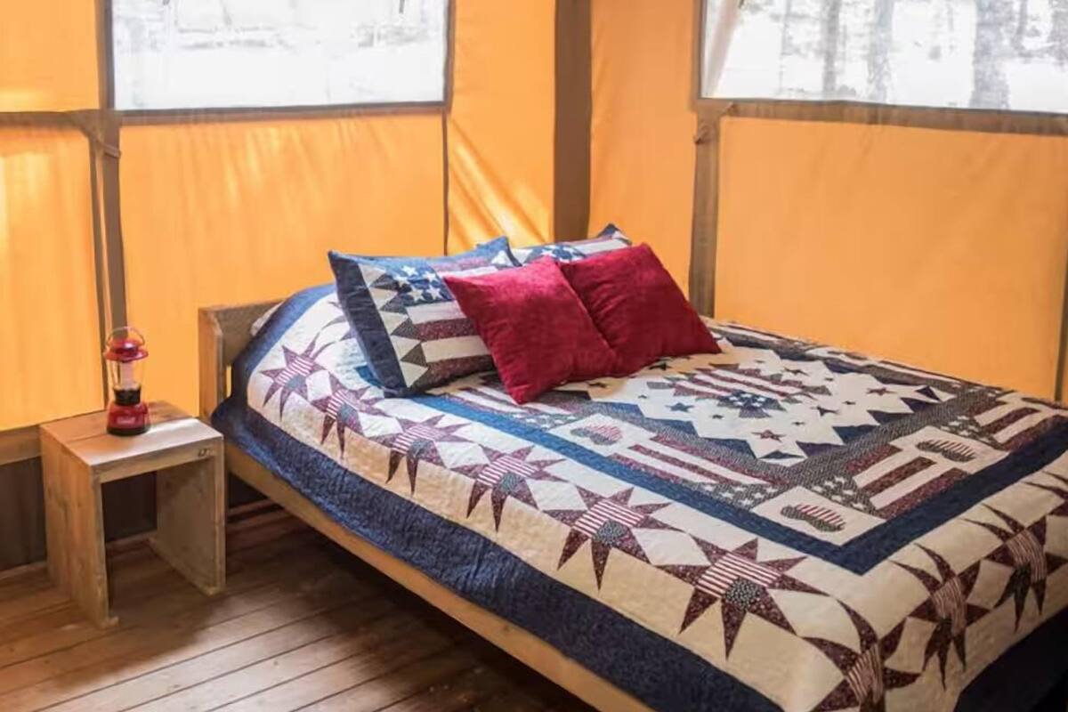 Una habitación con carpa, una cama, una mesita y una ventana.