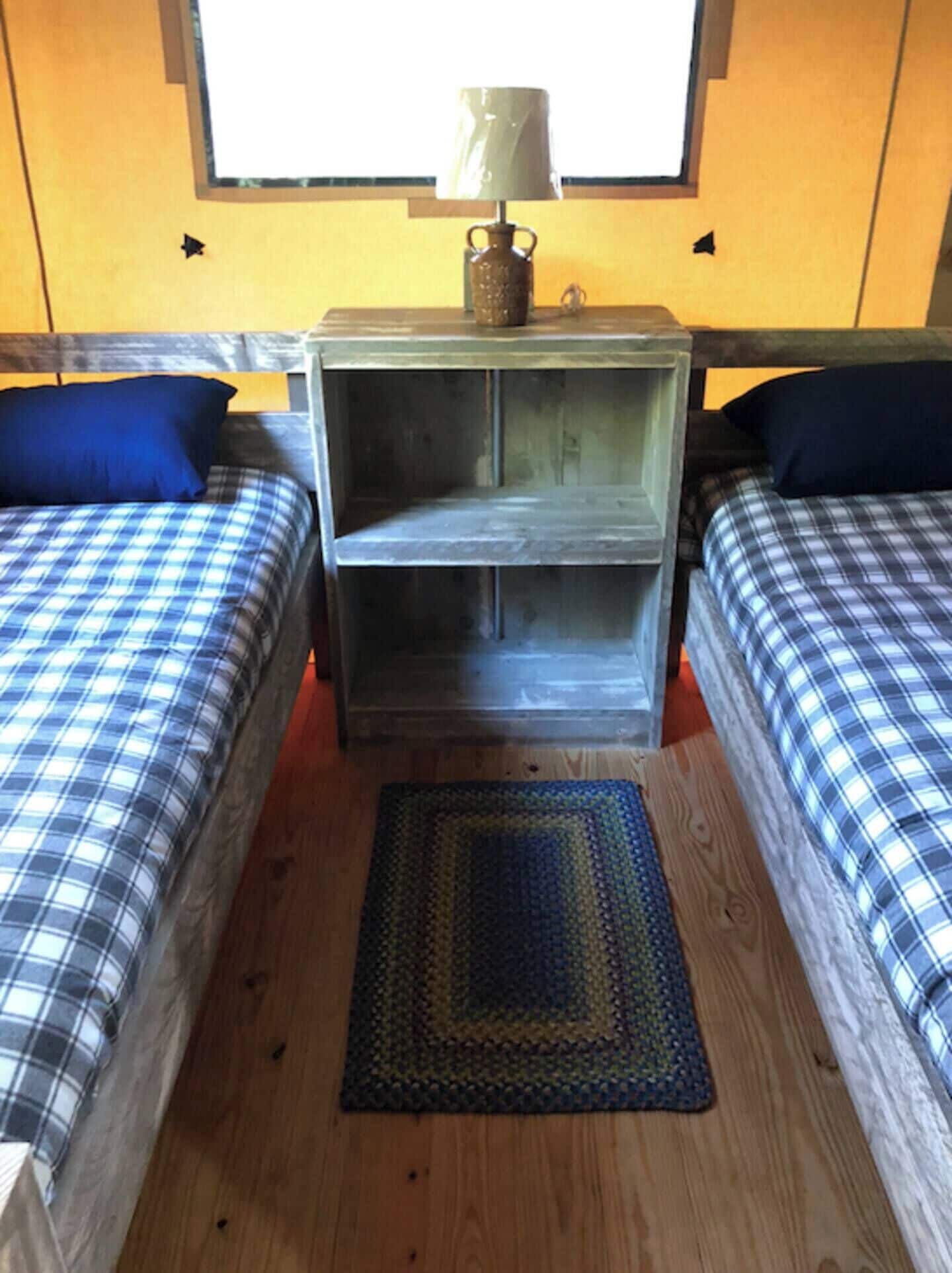 Una habitación con dos camas, una mesita de noche con lámpara y una ventana.