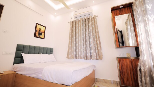 A neatly arranged bedroom with a bed, bedside table, and a mirror. - Wind Castle (Kanayannur)
