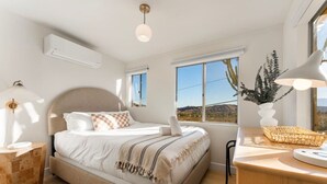 Una camera da letto con un letto, comodini, una scrivania, una lampada e una finestra con vista.
