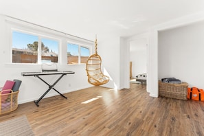 Ein Zimmer mit Holzboden, einem Hängekorbstuhl, einer Tastatur und einem Korbwannenkorb.