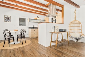 Eine moderne Küche mit Holzbalken, einem Hängesessel und einem Essbereich mit Stühlen und einem Tisch.