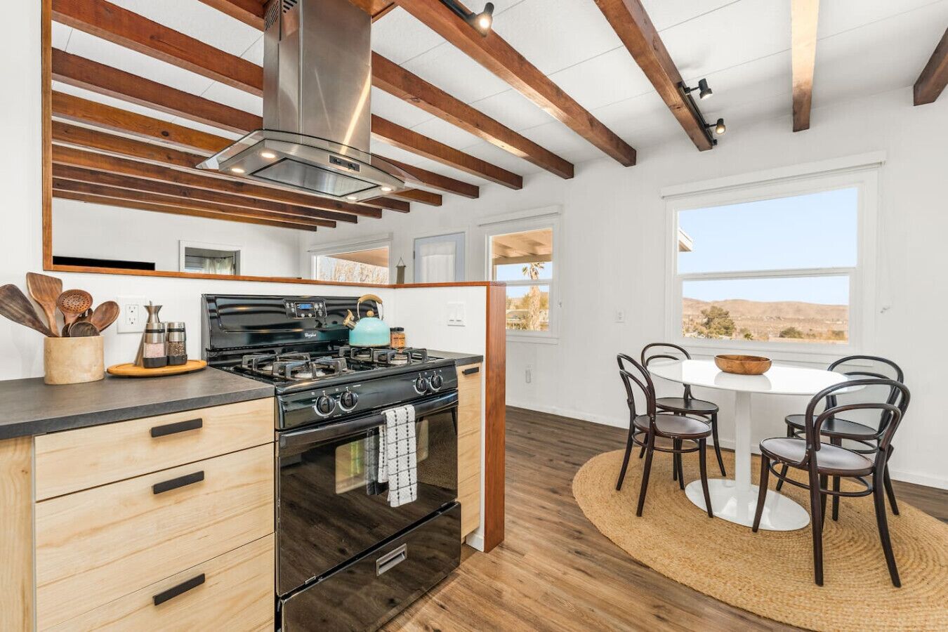 A kitchen with a stove, oven, and wooden ceiling beams.