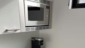 Een keuken met een magnetron, koffiezetapparaat en een lade met bestek.