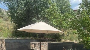 Een terras buiten met een tafel, stoelen, een parasol en een stenen muur.