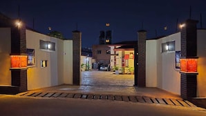 A gated entrance to a building at night with illuminated signs and a paved pathway leading to the entrance. - NEKST Hotel (Ibadan)