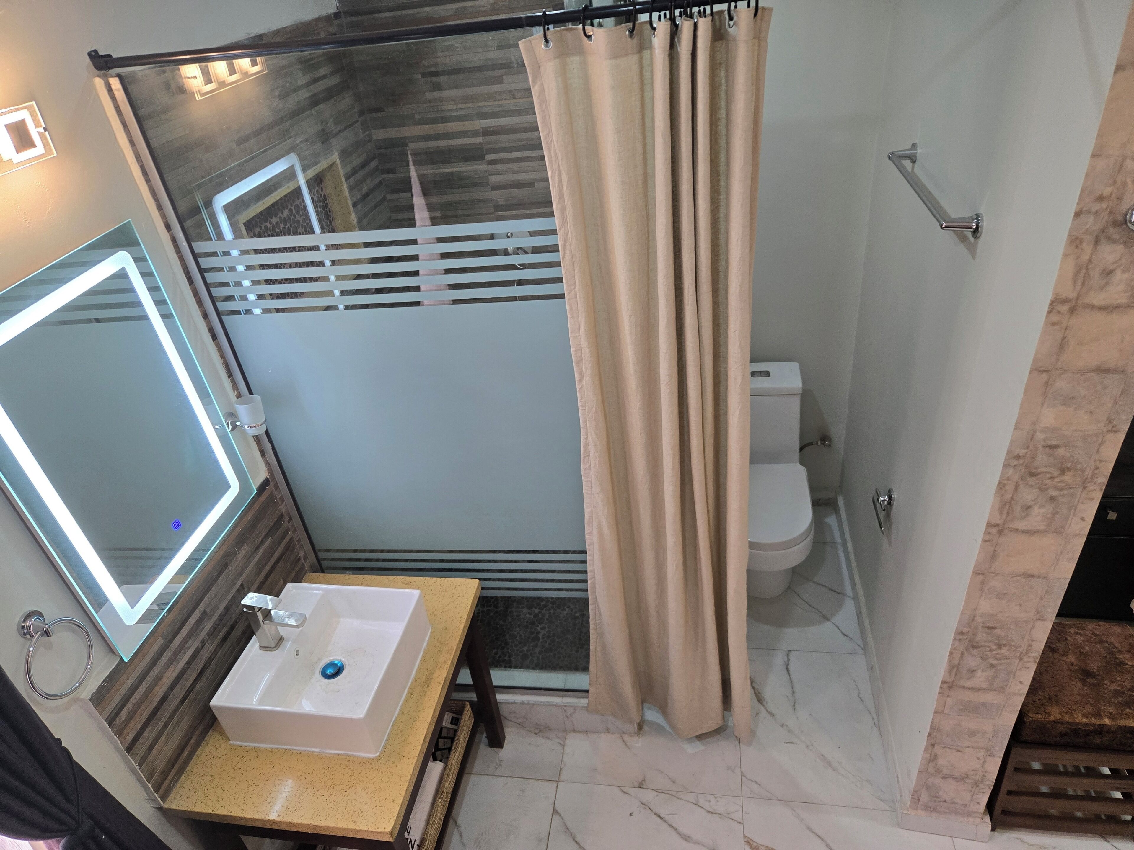 Une salle de bain avec un miroir, un lavabo, des toilettes et un rideau de douche.