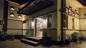 A building with a covered entrance, potted plants, and a staircase leading to an upper level. - NEKST Hotel (Ibadan)