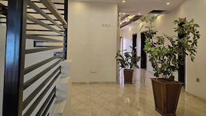 A modern interior with a staircase, marble flooring, and potted plants. - NEKST Hotel (Ibadan)