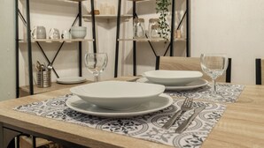A dining table set with white plates, bowls, and cutlery, accompanied by wine glasses.