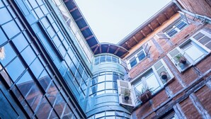 A modern building with a unique corner design, featuring large windows and a mix of brick and glass facades.