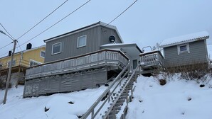 A two-story building with a wooden staircase leading to a balcony. - Sørøya: Skipper view Akkarfjord, 210m from pub, diner and quay. Sørøya along the coast! (Finnmark)