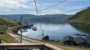 A coastal view with a dock, boats, and houses by the water. - Sørøya: Skipper view Akkarfjord, 210m from pub, diner and quay. Sørøya along the coast! (Finnmark)