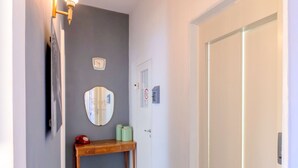 A hallway with a wooden bench, a wall clock, a mirror, and a door. - mimi terrace (Naples)