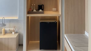 Et moderne køkken med indbyggede træhylder, et sort køleskab og en bordplade med en lampe og køkkenudstyr.