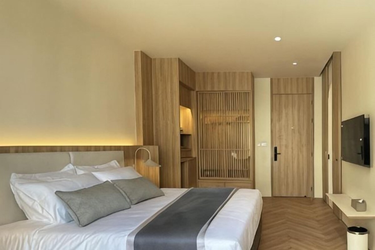 A hotel room with a bed, bedside table, TV, and a wardrobe.