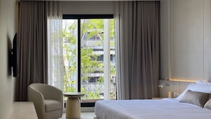 Et moderne hotelværelse med en stor seng, en sofa, et lille bord og et fjernsyn ophængt på væggen.