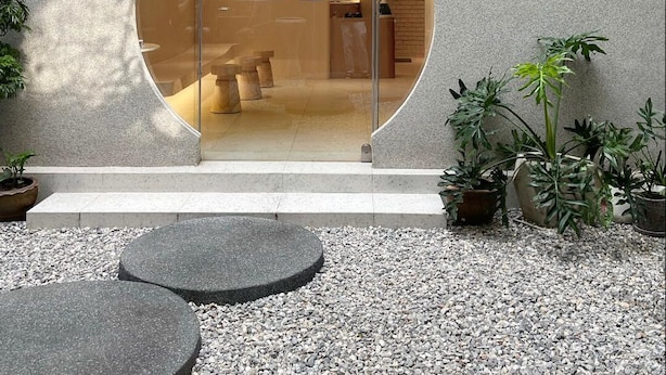 En spa-entré med receptionsdisk, et navneskilt og en grussti, der fører hen til indgangen.