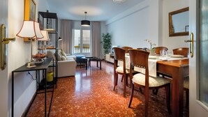 A modern hotel room with a dining area, a sofa, a table with chairs, and a large window with curtains. - MARA ARENAL. AMPLIO APARTAMENTO EN EL CENTRO DE SEVILLA IDEAL PARA FAMILIAS (Sevilla)