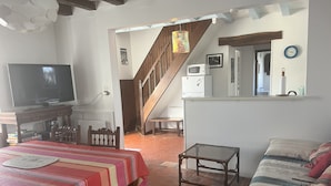 A cozy living room with a television, a striped table, a sofa, and a staircase leading to another room. - Gîte in the heart of the Loire castles (Athée-sur-Cher)