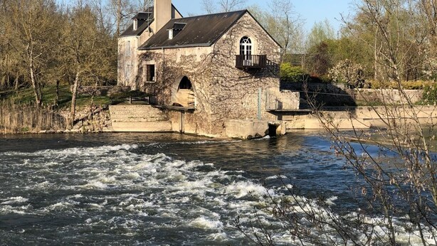 A stone building with a balcony, situated by a river with flowing water. - Gîte in the heart of the Loire castles (Athée-sur-Cher)