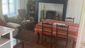 A dining area with a fireplace, wooden chairs, and a striped tablecloth. - Gîte in the heart of the Loire castles (Athée-sur-Cher)