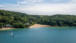A coastal landscape with a beach, boats, and a sailboat.