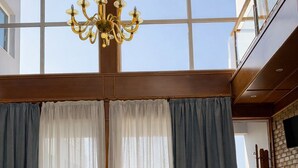 A spacious living room with a large window, a chandelier, and two sofas. - Blue Escape (Nafplio)