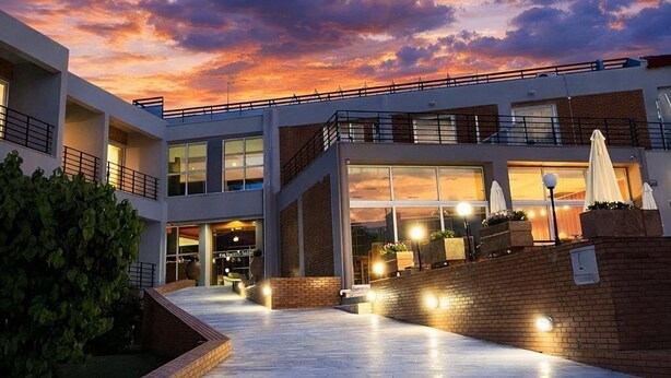 A modern building with a spacious outdoor area, a covered seating area, and a view of the sky at dusk. - Blue Escape (Nafplio)