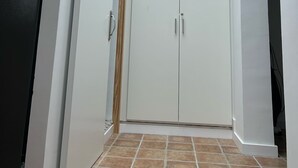 Huoneessa on kattovalokuvio, valkoiset seinät ja laatoitettu lattia.