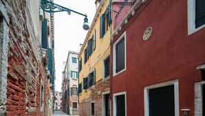 A narrow cobblestone street flanked by historic buildings with exposed brick walls and colorful facades. - Cá delle Capriate, an intimate retreat at Cà d'Oro (Venezia)