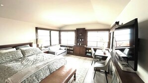 Une chambre d’hôtel moderne avec un grand lit, un bureau, une chaise, une télévision et une fenêtre.