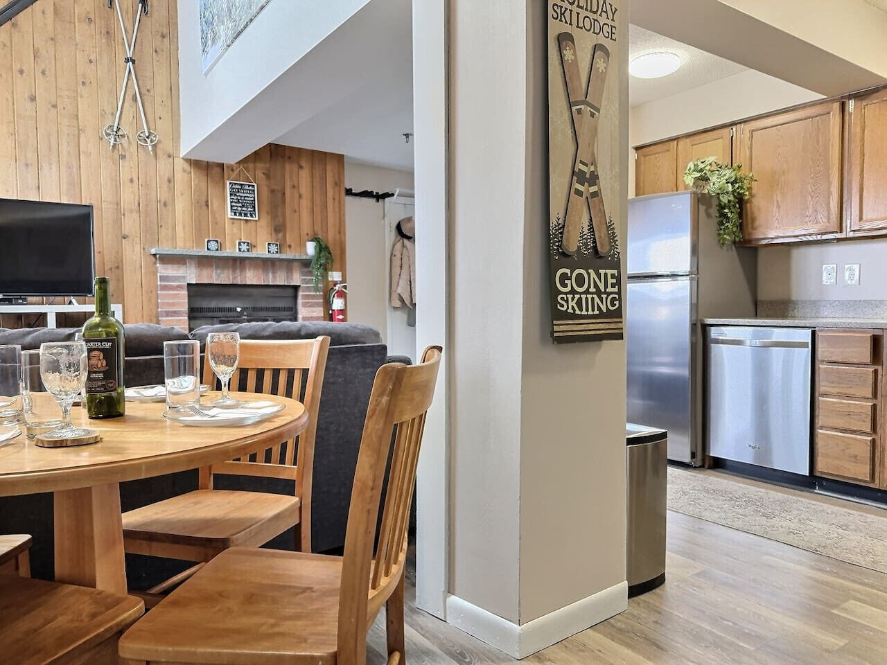 A modern kitchen with wooden cabinets, a stainless steel refrigerator, and a dining area with a wooden table and chairs.