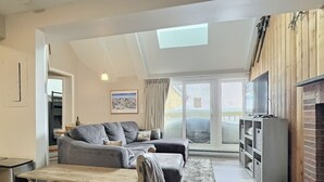 A modern living room with a grey sofa, a wooden coffee table, and a fireplace. - BearNecessities- Pool, Hot Tub, Gym (Killington)