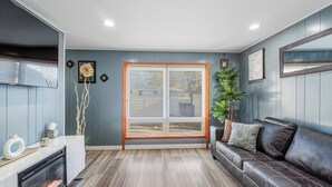 Una sala de estar moderna con un ventanal grande, chimenea, sofá de cuero y decoración minimalista.