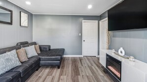 Una sala de estar moderna con un sofá modular, una chimenea y un televisor de pantalla plana montado en la pared.